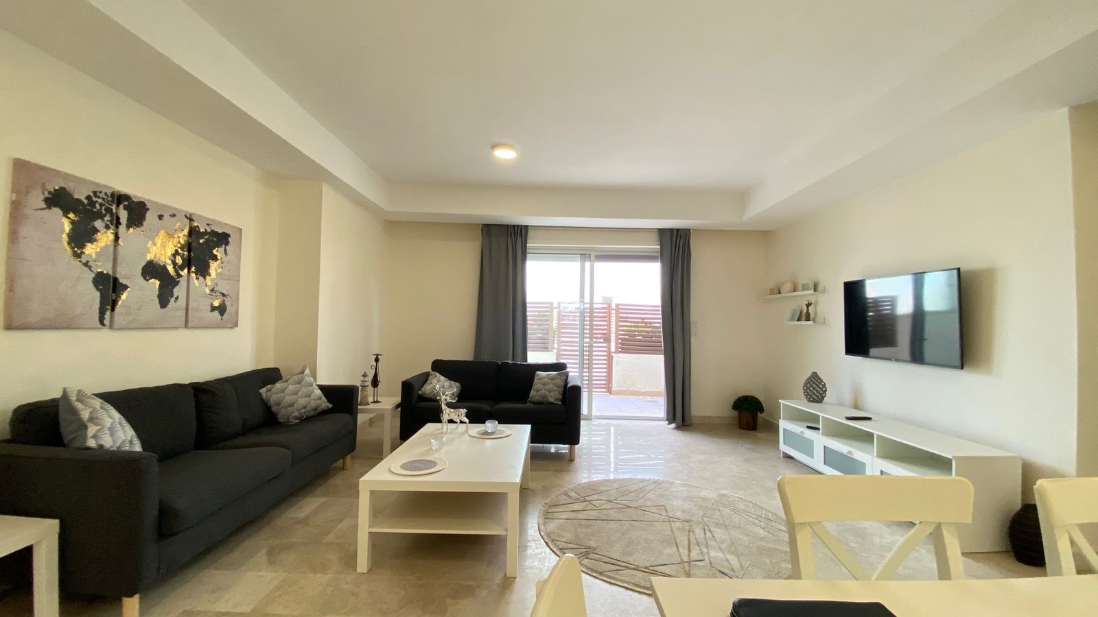 07a650eb-eeb9-4968-9924-4fb88e8f1ec6 Living room with two dark gray sofas, white coffee table, and world map wall art above the sofa.