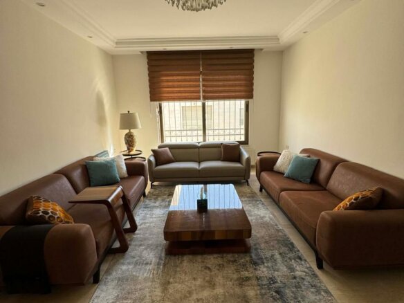 Cozy living room with brown leather sofas facing a gray sofa, a wooden coffee table, and a crystal chandelier overhead.