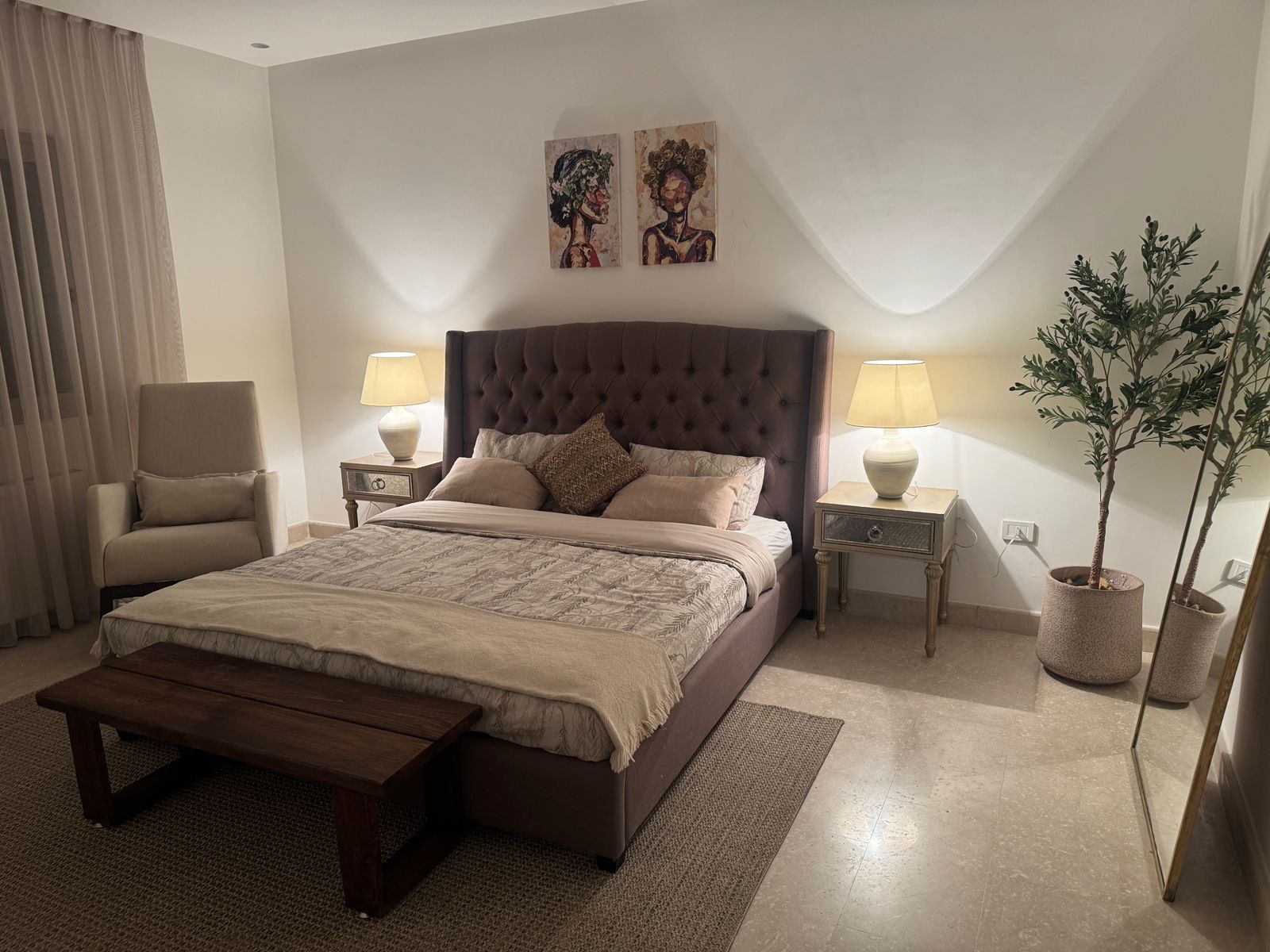 4448d83f-132a-45fd-a76c-022d55028083 Elegant bedroom with a tufted purple bed, two nightstands with lamps, and beige bedding.