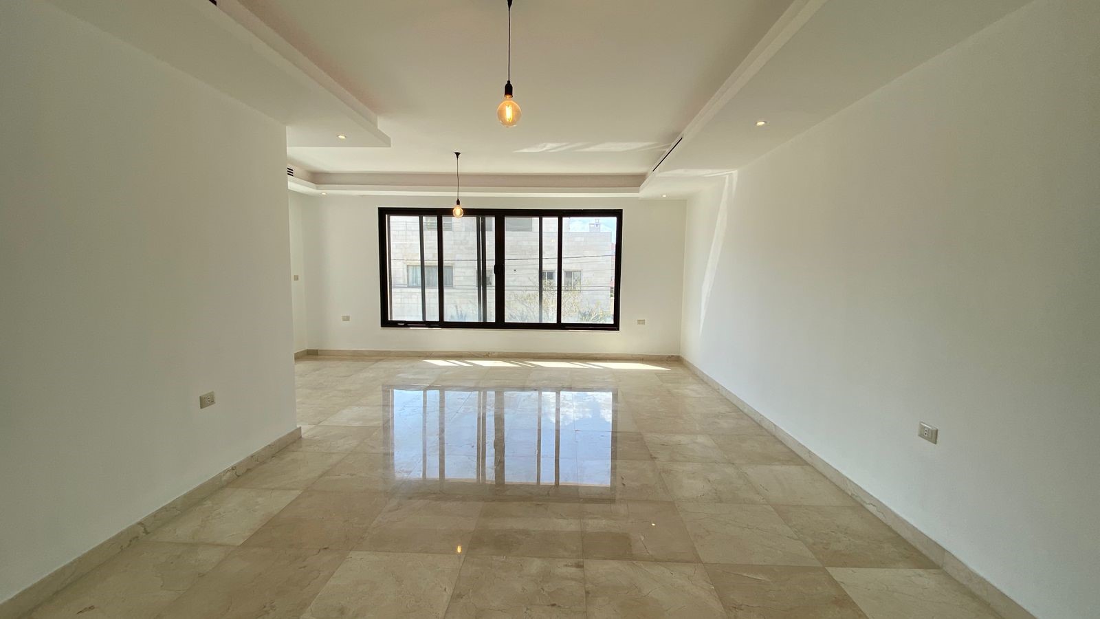 6fe82730-2193-4b4d-ac6e-bfbc41863d2e Empty modern living room with a large black-framed window, white walls, and glossy beige marble floors.