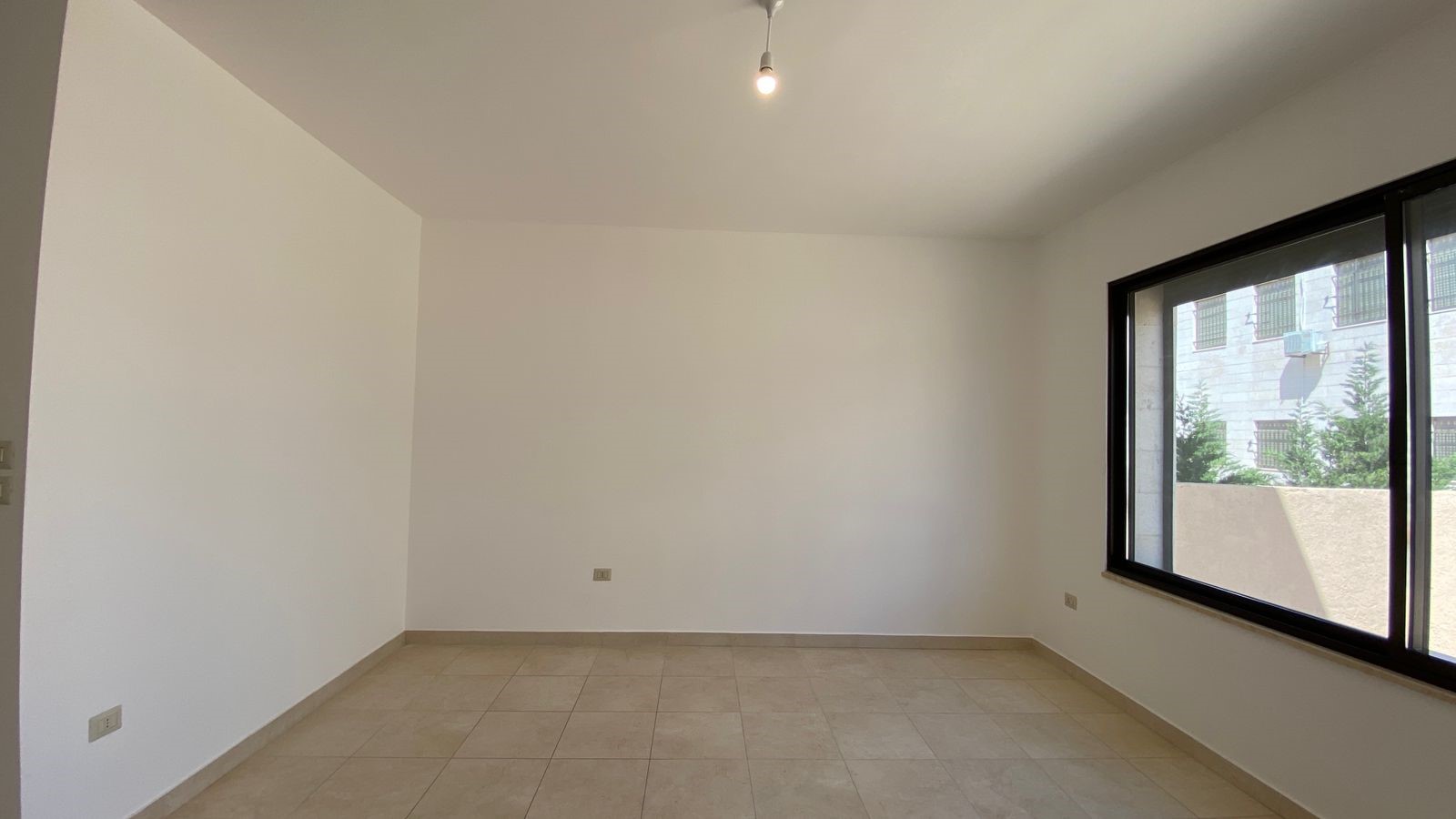 8dd860a7-37e2-41ad-b6d3-f11b588029b9 Empty room with beige tile floor, white walls, and a large daylight-filled window on the right.