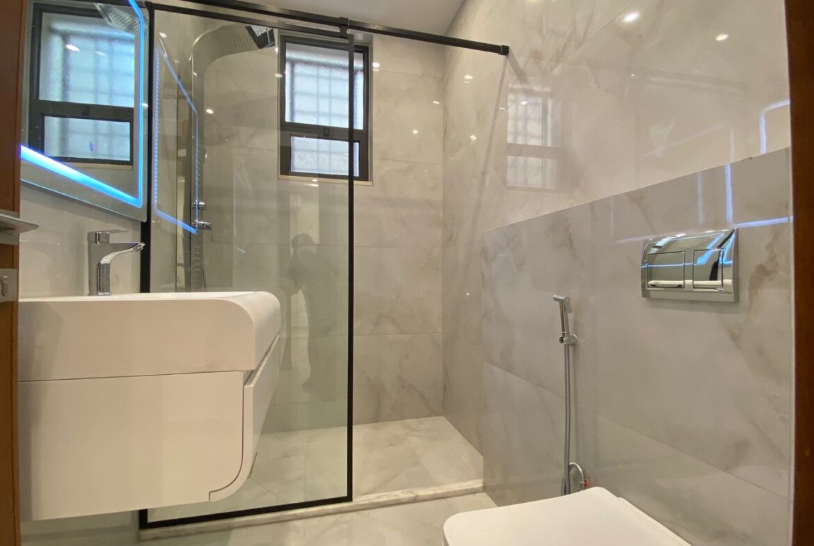 Modern bathroom with white marble tiles, a glass shower enclosure, and a wall-mounted sink with chrome faucet?