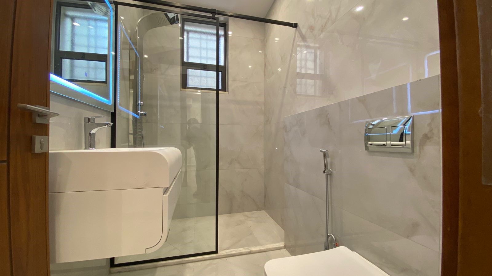 9253f123-ac82-4a48-9933-d5590d653912 Modern bathroom with white marble tiles, a glass shower enclosure, and a wall-mounted sink with chrome faucet?