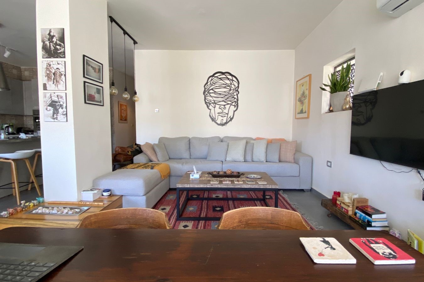 Living room with a gray sectional sofa, wall art of a tangled-head silhouette, and a coffee table on a red rug.