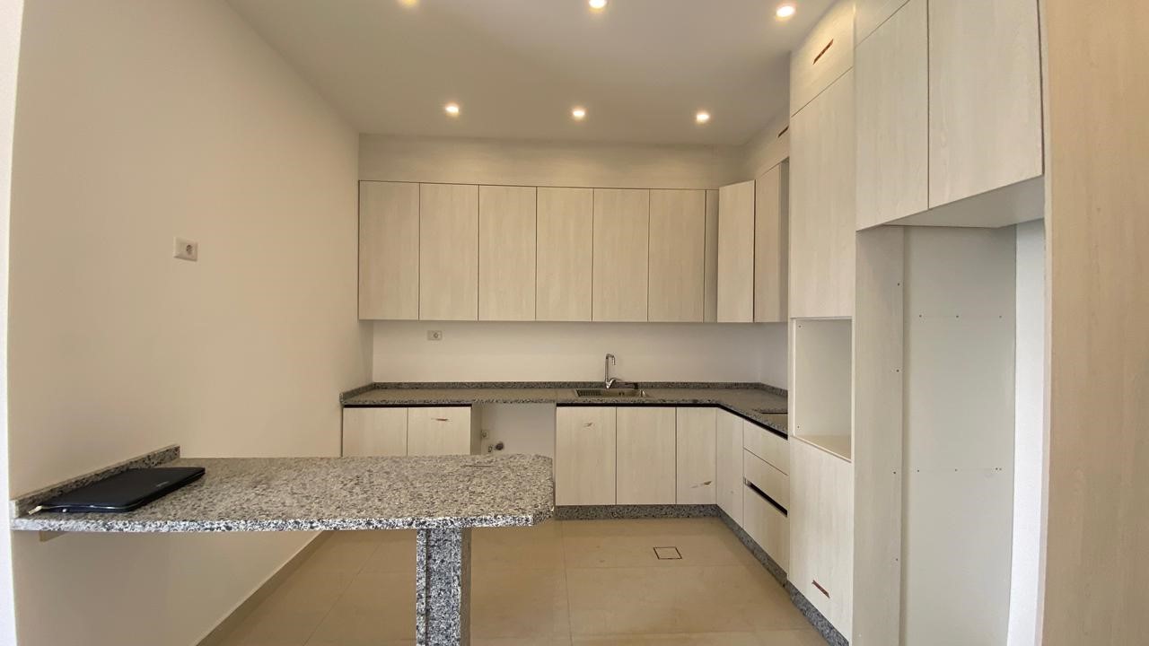 9e6dd7e3-341b-480a-820f-02782b7e1e0f Modern L-shaped kitchen with light wood cabinets, speckled granite countertops, and an island with a granite top.