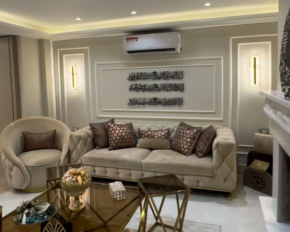 b0b5ebca-0903-436f-9d46-9b5c4c481b76 Elegant living room with a tufted cream sofa, round armchair, and gold coffee tables in a softly lit, modern space.