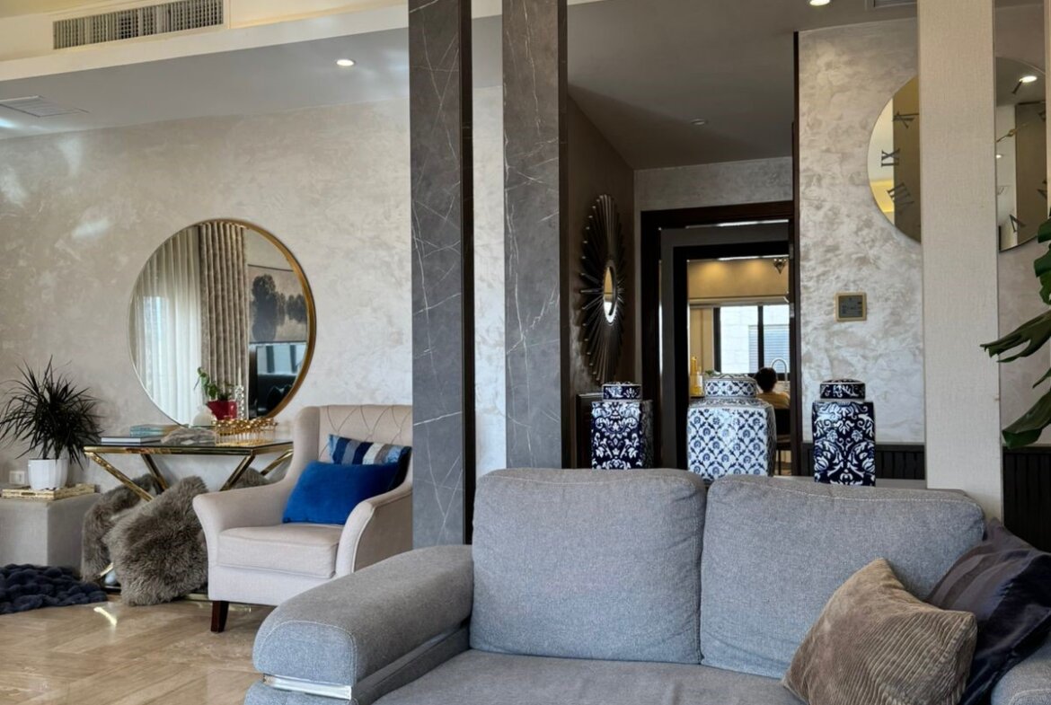 Luxurious living room lobby with a crystal chandelier, gray sofa, and decorative blue cushions.