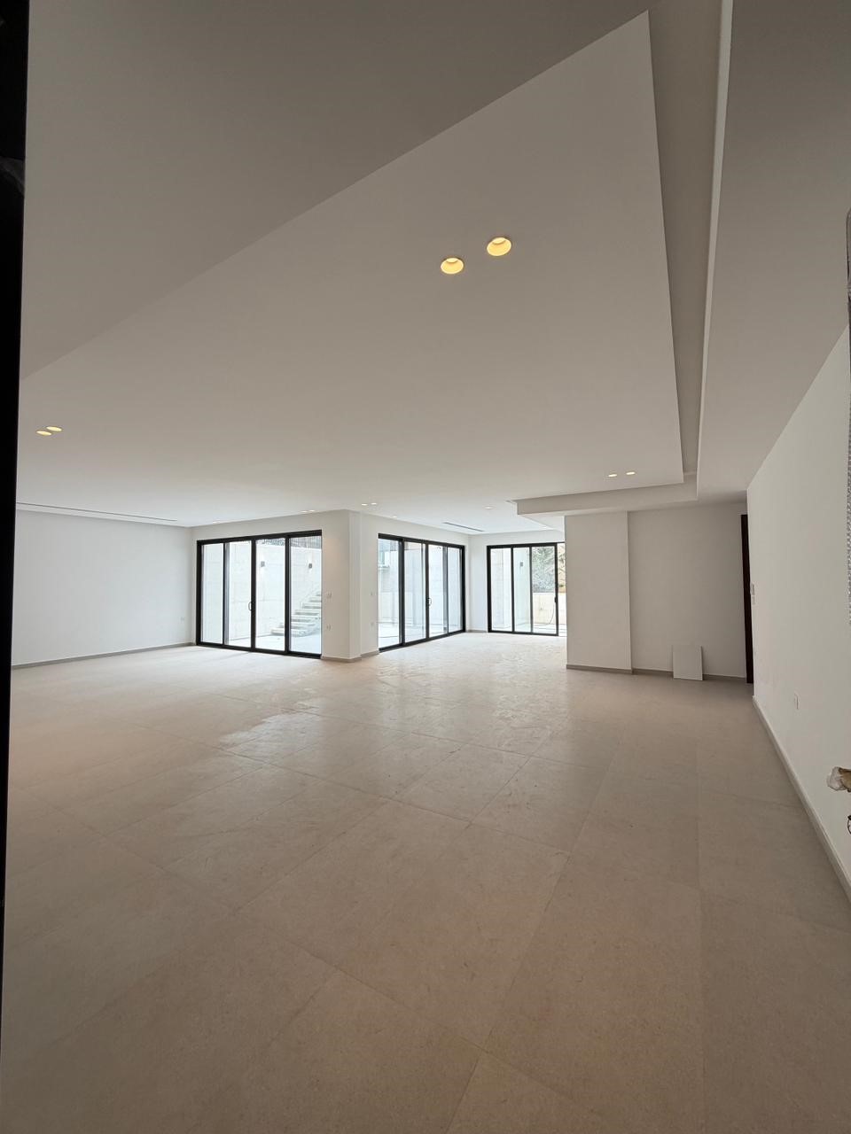 d5ebb857-864f-4595-bb12-a4769db347f1 Spacious empty living area with white walls and large floor-to-ceiling glass doors opening to an exterior space.