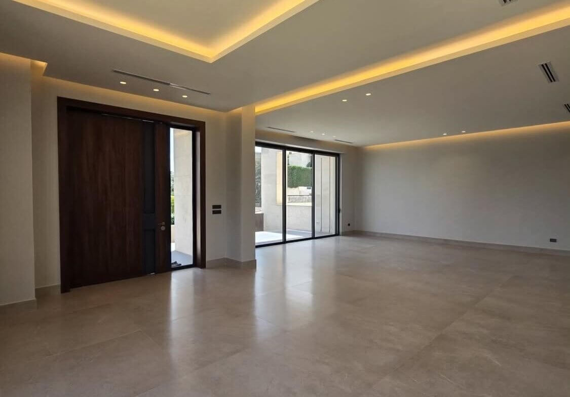 05f5861e-6546-4ce7-b787-e1d6b15da044 Spacious, unfinished living room with large sliding glass doors to an outdoor area and a dark wood entry door on the left.