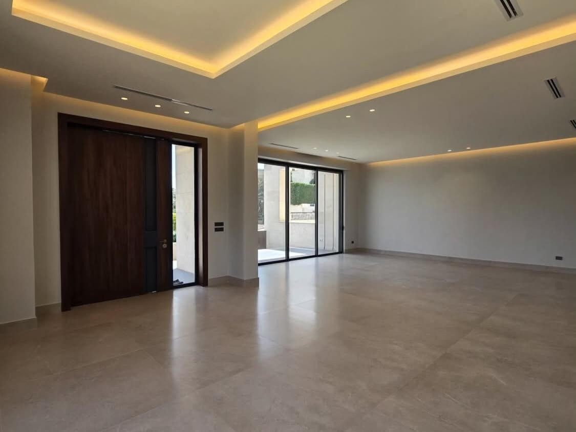 05f5861e-6546-4ce7-b787-e1d6b15da044 Spacious, unfinished living room with large sliding glass doors to an outdoor area and a dark wood entry door on the left.