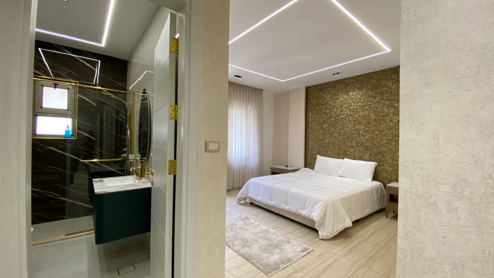 1f885209-13cb-4587-baca-c635bfcf586d Modern hotel bedroom with white bedding, beige curtains, and a gold mosaic accent wall behind the bed.