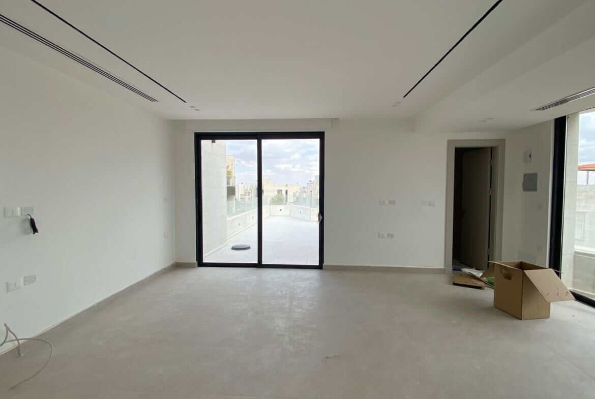 Empty modern living room under construction with large glass sliding doors to a balcony
