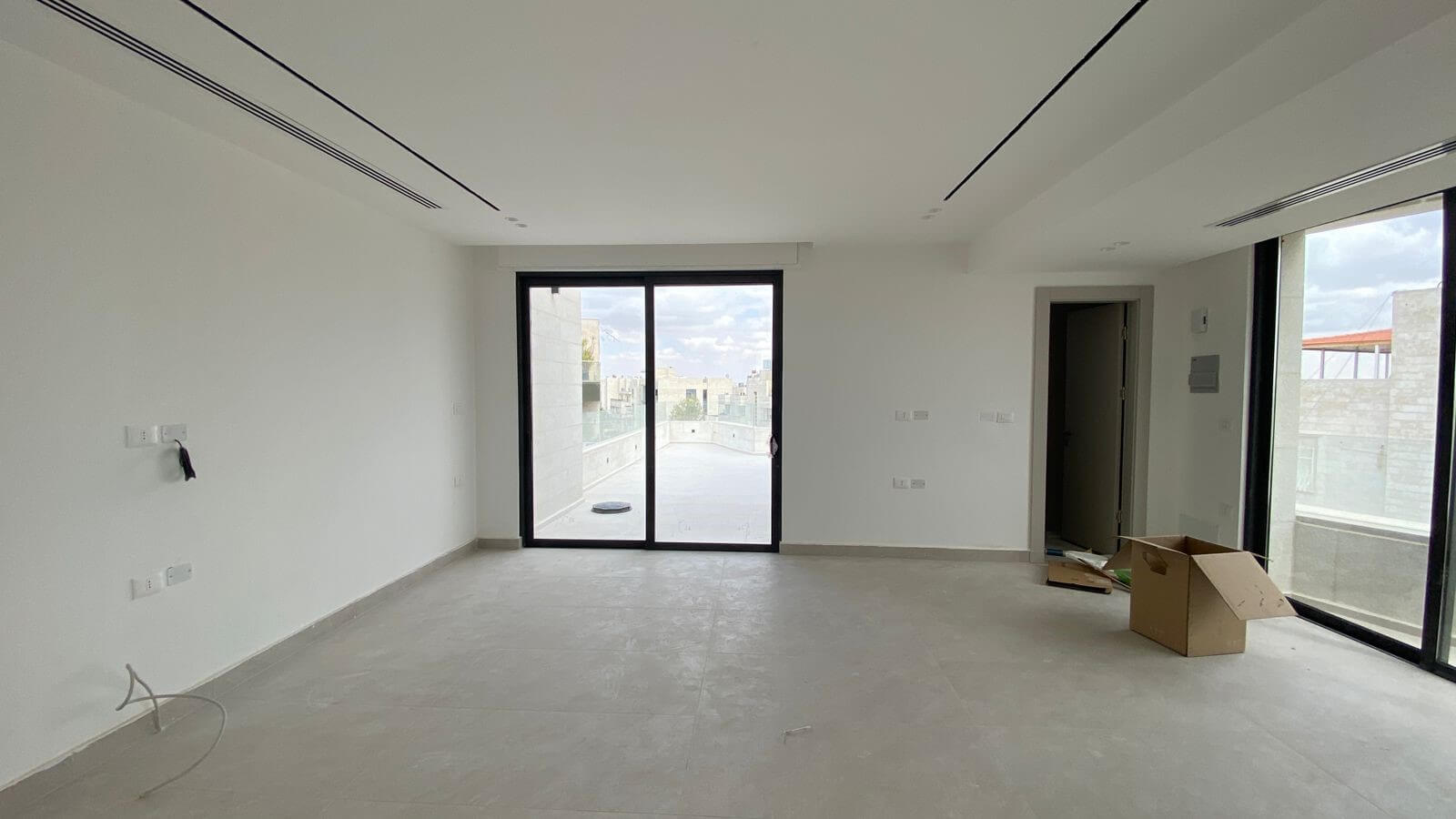 Empty modern living room under construction with large glass sliding doors to a balcony
