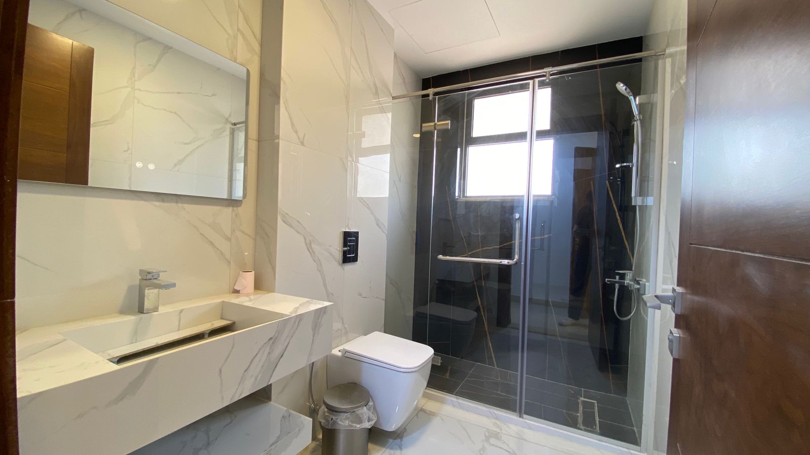 3f32263d-9185-42a4-b308-1f23b28b7cb5 Modern bathroom with marble vanity, wall mirror, and a wall-mounted sink. (White and gray tones)
