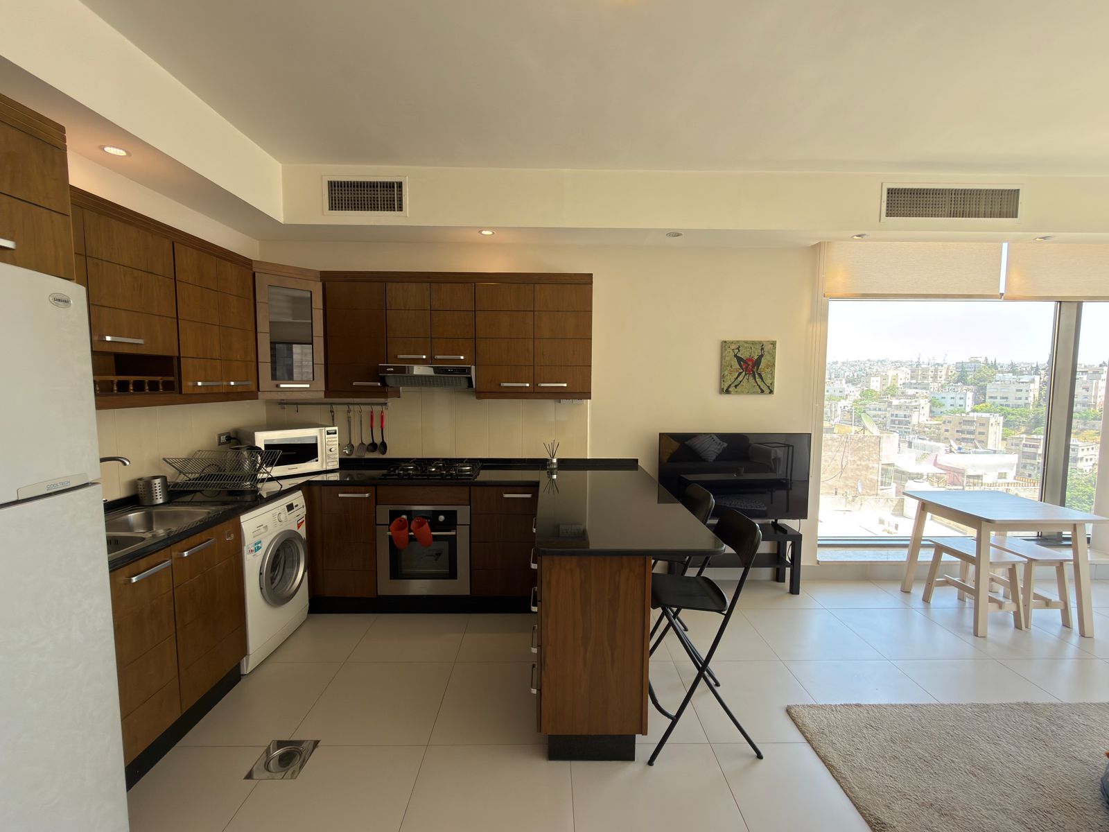 4edb7971-1853-444a-ac42-51fc6c8e3193 Modern kitchen with dark wood cabinets, a stainless steel oven, and a kitchen island facing a large window with city view