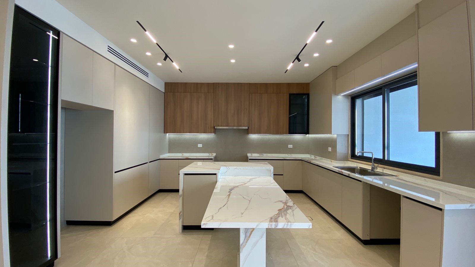 6cc2b857-5629-4b24-9097-ca16dfa502f2 Contemporary kitchen with marble countertops, beige lower cabinets, wood upper cabinets, and a central marble island.