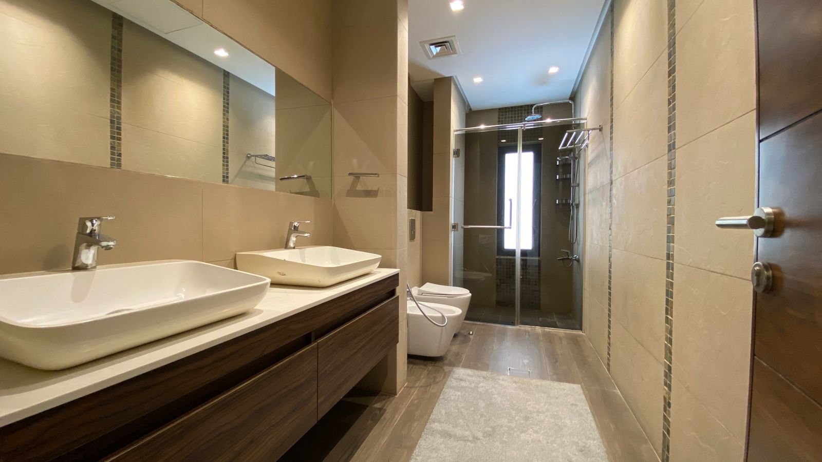 713c55cc-ad66-449a-8dd2-180a3cf6a4eb Modern bathroom with dual rectangular vessel sinks on a wood vanity, large mirror, and glass-enclosed shower in neutral tones.