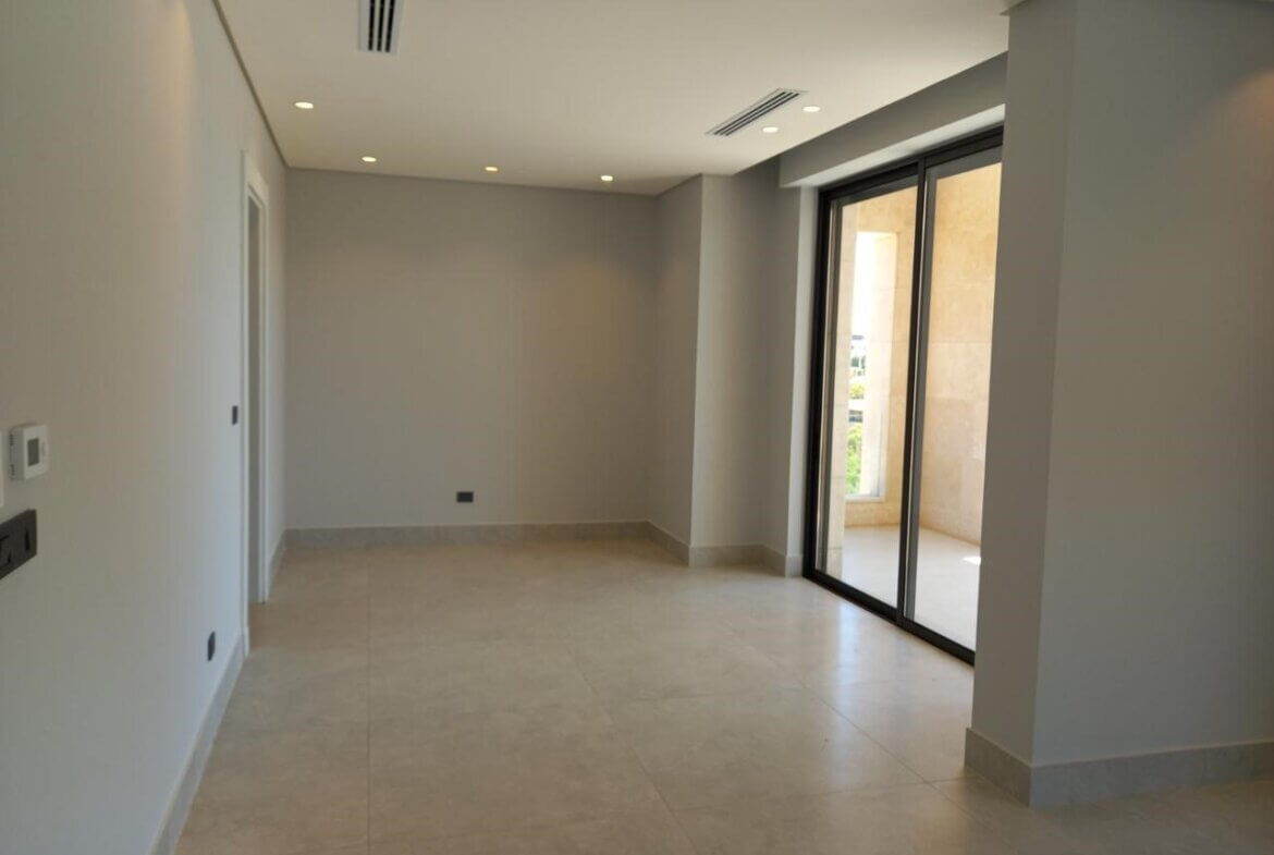 8d755a7f-99bc-40f8-953e-c1862890ca39 Empty modern living area with large sliding glass doors to a balcony, neutral gray walls, and light tiled floor.