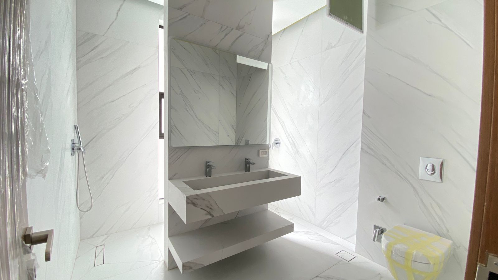 90423b84-1d65-481b-802a-e0e274d7b1c4 Modern marble bathroom with a floating double sink vanity, large mirror, and glass-walled shower area on the left.