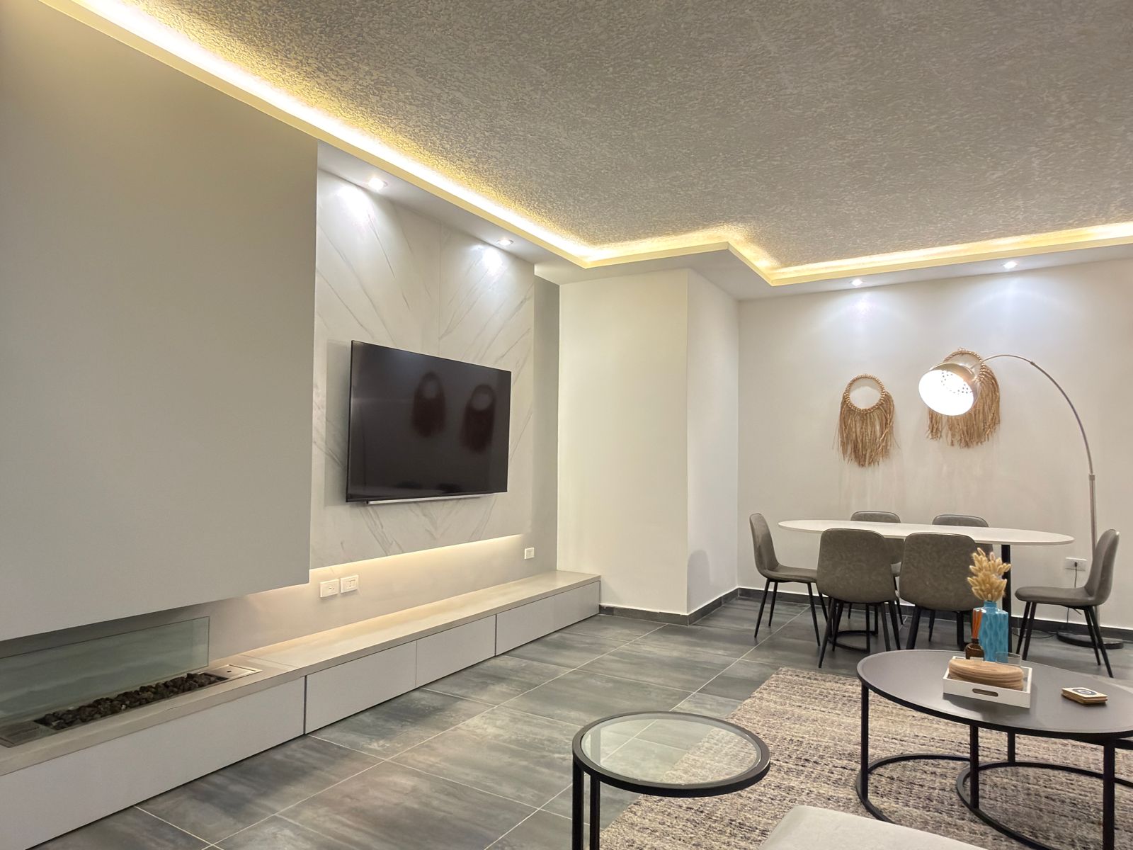 WhatsApp Image 2026-05-07 at 84333 PM 3 Modern living/d dining area with wall-mounted TV on a marble accent wall and recessed ceiling lighting