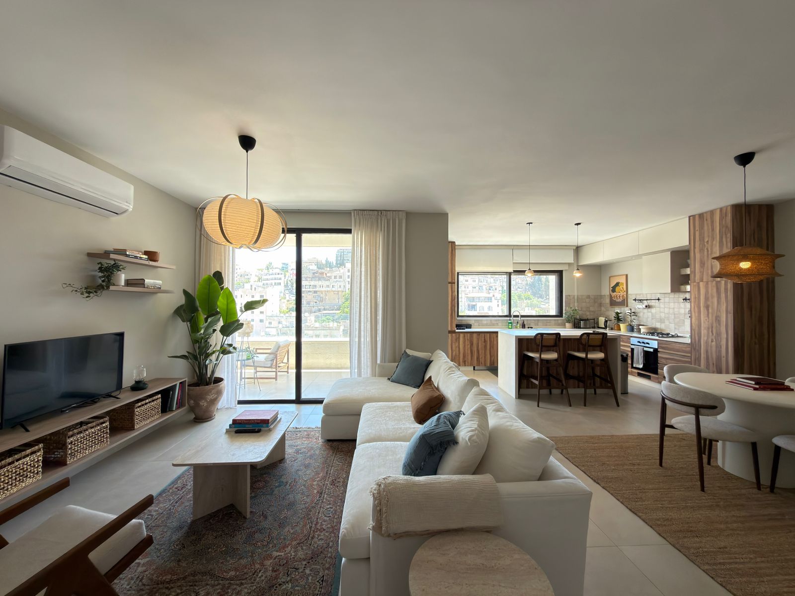 b82b16a8-6448-4dae-b9ed-704a6dd16245 Open-plan living room and kitchen with a white sofa, wooden accents, and a balcony view. (informative)