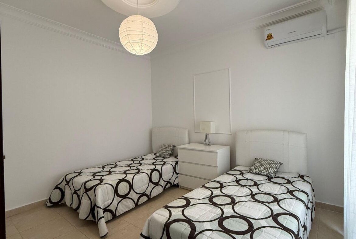 Twin bedroom with two single beds, white headboards, and circle-pattern black-and-white quilts.
