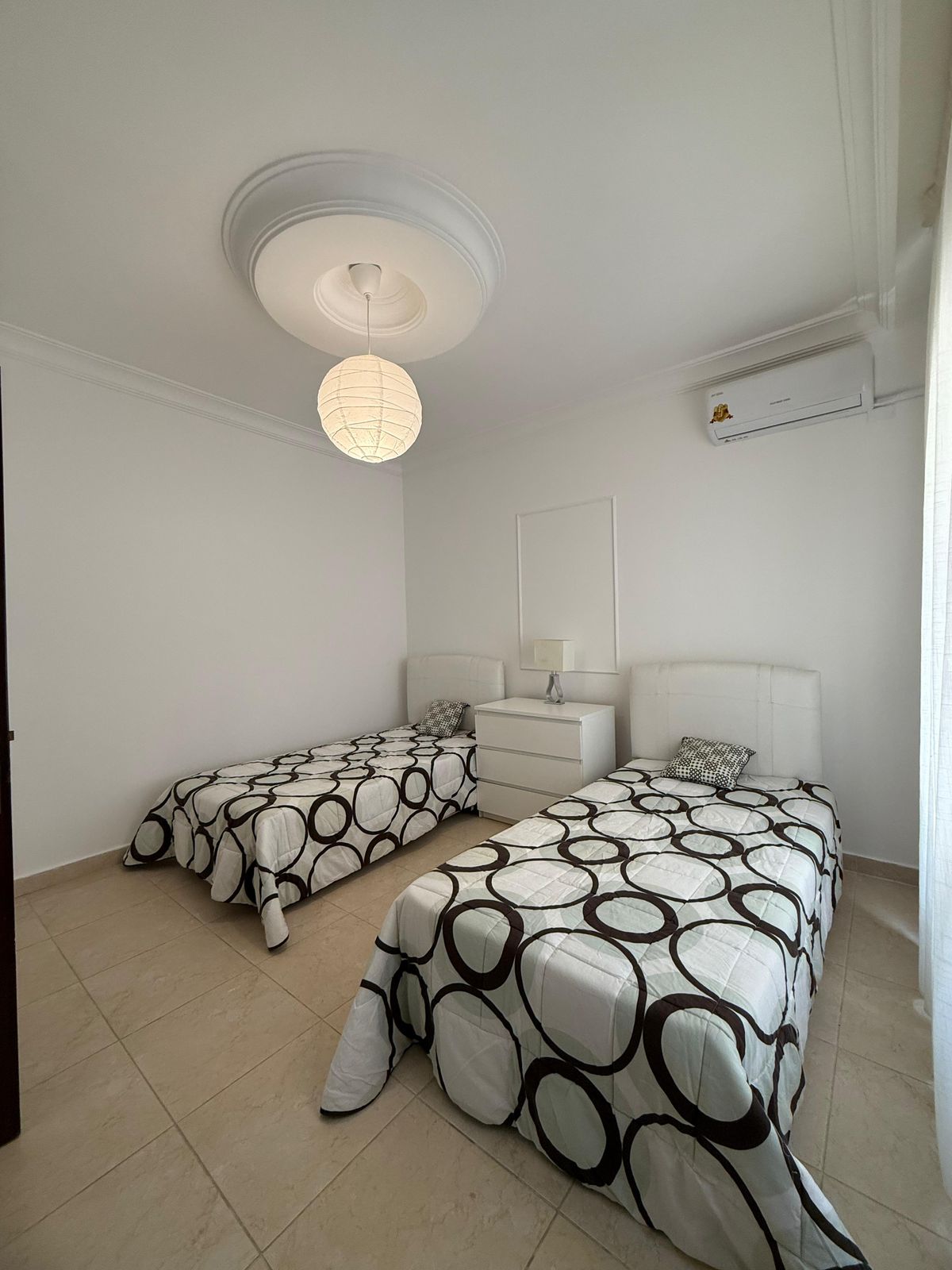 Twin bedroom with two single beds, white headboards, and circle-pattern black-and-white quilts.