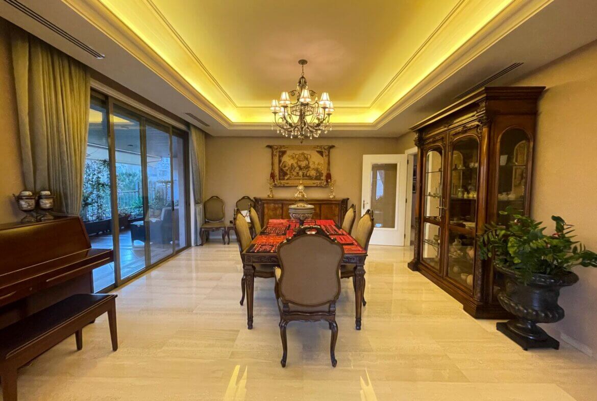 140235d3-56e1-4dde-a9ea-4072b26e227e Elegant dining room with a dark wood table and six chairs, ornate chandelier overhead, and a glass-front cabinet nearby.