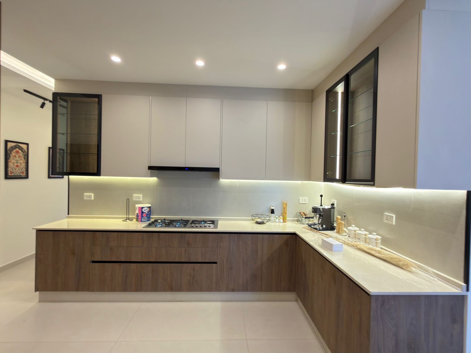 20e30c0b-ea9e-43ff-b70e-3293ae58c09b Modern kitchen with a large island, gray upper cabinets, and glass-front display cabinets along the wall.