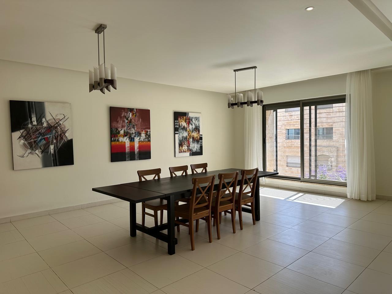 2657ac28-b24c-4b7a-b5ad-8b356f0c8a2c Modern dining room with a long dark table, eight wooden chairs, abstract art on the wall, and a large window with white curtains.