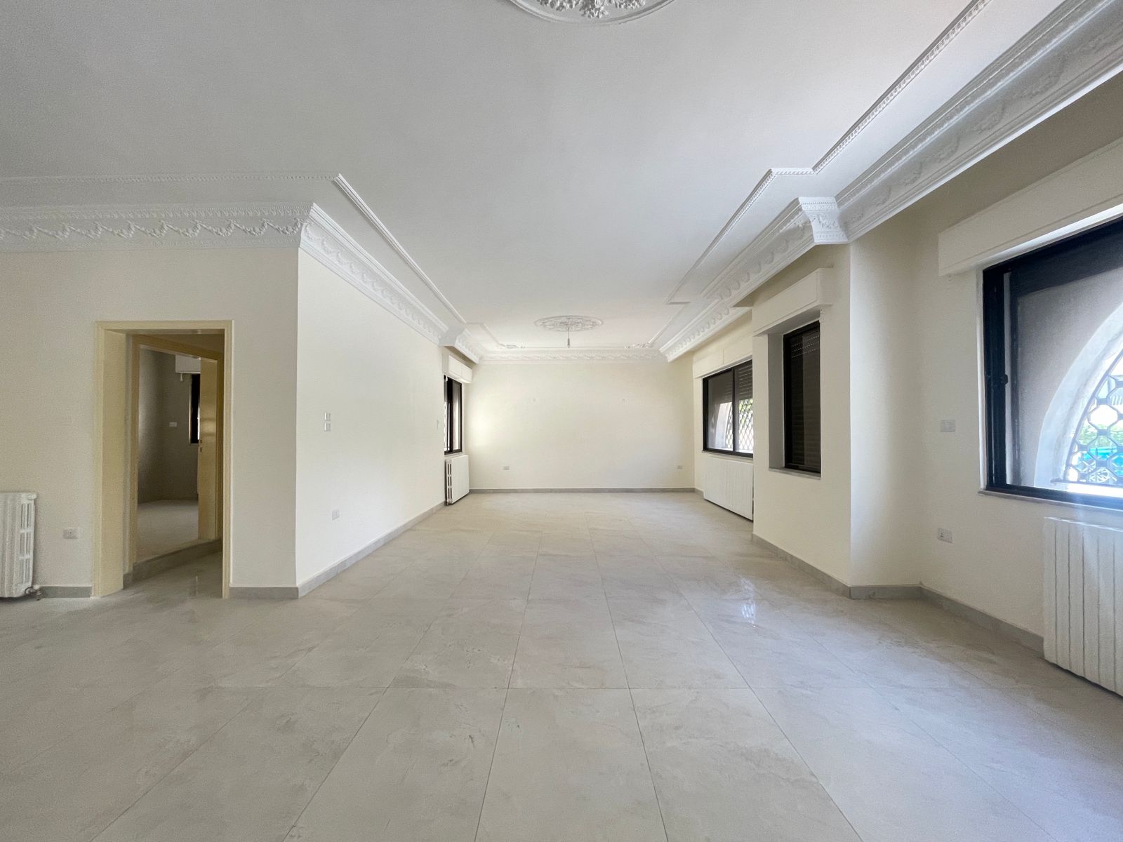 26dd92a8-168b-4954-a2fe-bbff7312c058 Spacious empty living room with white walls, ornate crown molding, and large windows