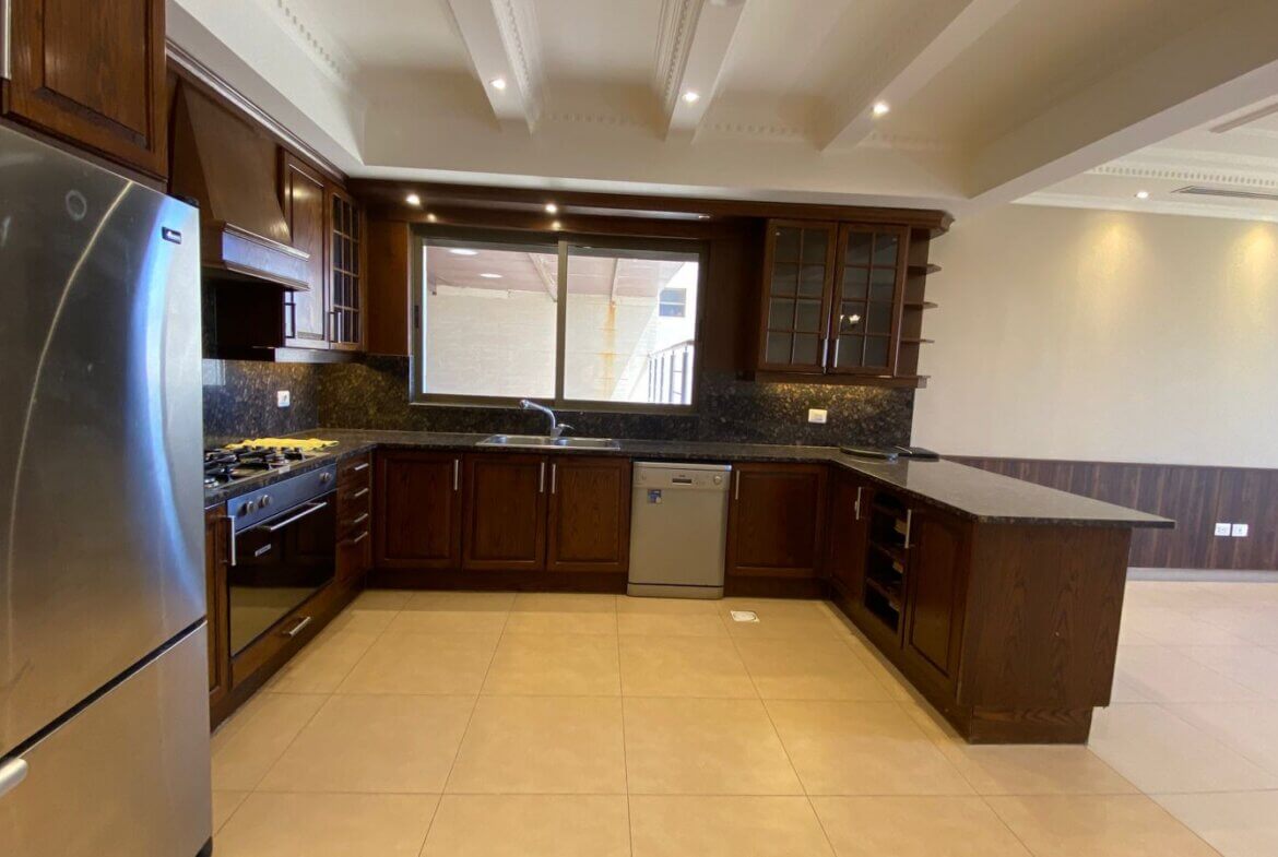 27ec30c4-1b0d-4e4a-8c6e-becbebfefdf5 Modern kitchen with dark wood cabinets, stainless steel fridge and range, central island, and tile floor.