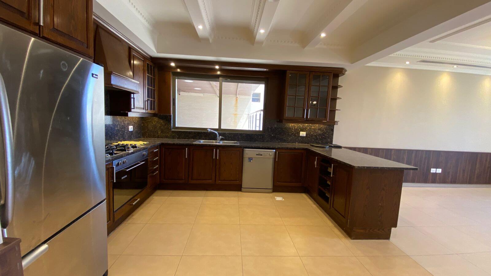 27ec30c4-1b0d-4e4a-8c6e-becbebfefdf5 Modern kitchen with dark wood cabinets, stainless steel fridge and range, central island, and tile floor.