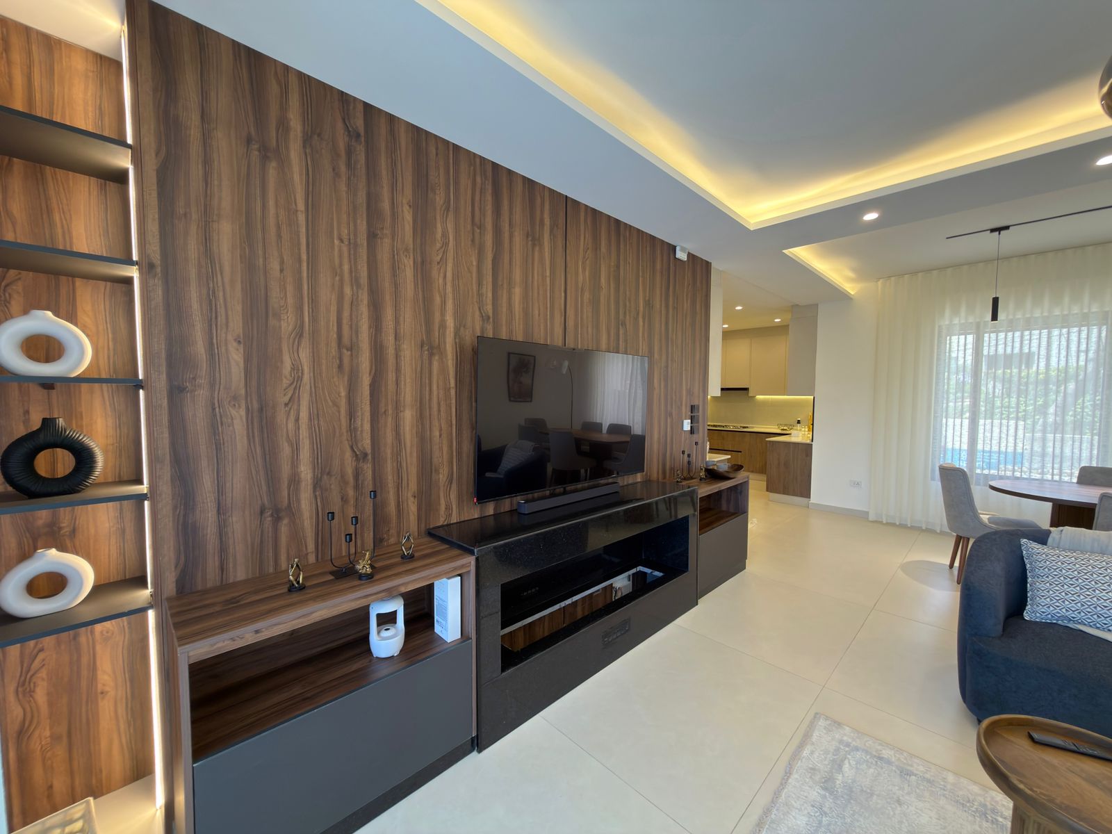 291f13a4-abdd-456e-a4e8-326cc93a3a71 Living room with a wood-paneled feature wall, mounted TV, and sleek black entertainment unit.