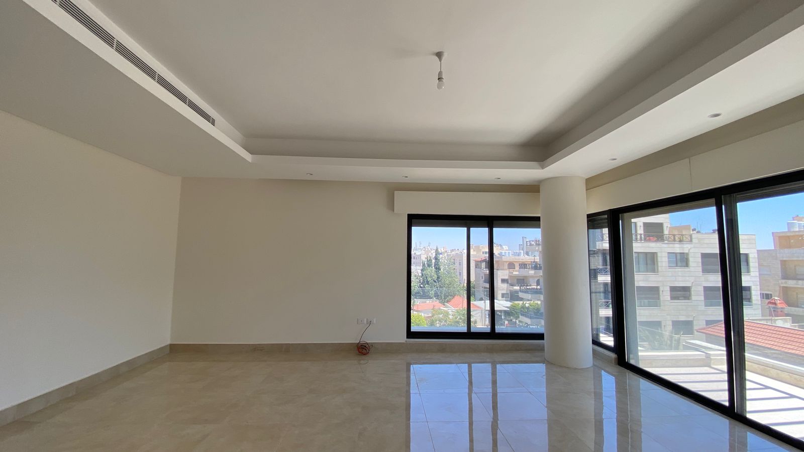 2b79f461-8c96-4cbf-a698-9f2373f7e63d Empty modern living room with large floor-to-ceiling windows and a city view outside