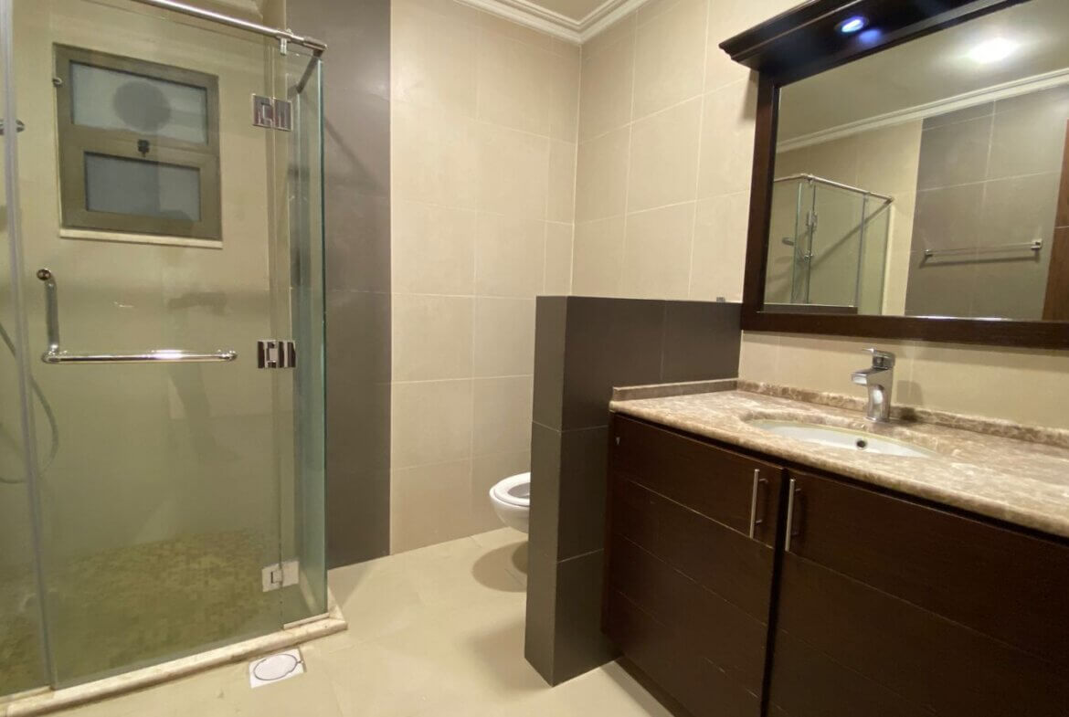 3b6fb577-706b-4d51-ad65-237ff6d267fe Modern bathroom with glass-enclosed shower, dark wood vanity, and marble countertop mirror above.
