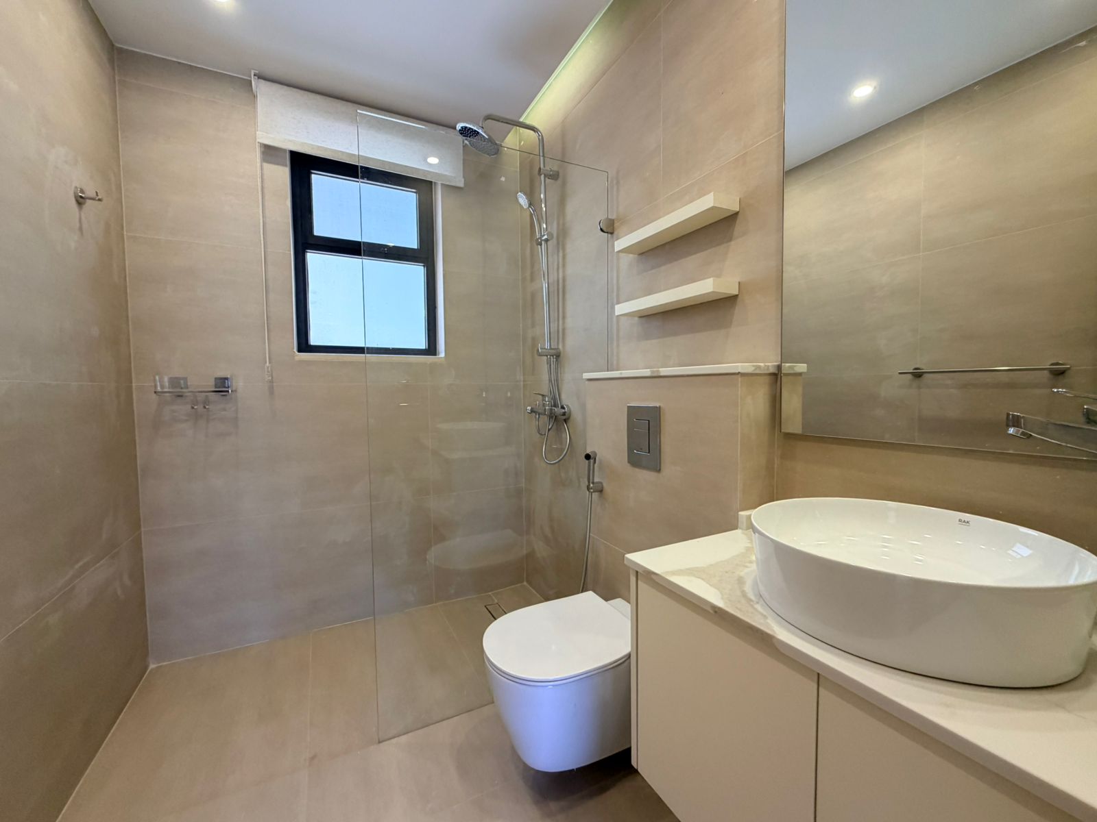 525f4e4b-0ae7-448b-ae64-2894c44aa7db Modern beige-tiled bathroom with glass shower enclosure, ceiling rain shower, handheld shower, and a windowed wall fixture.