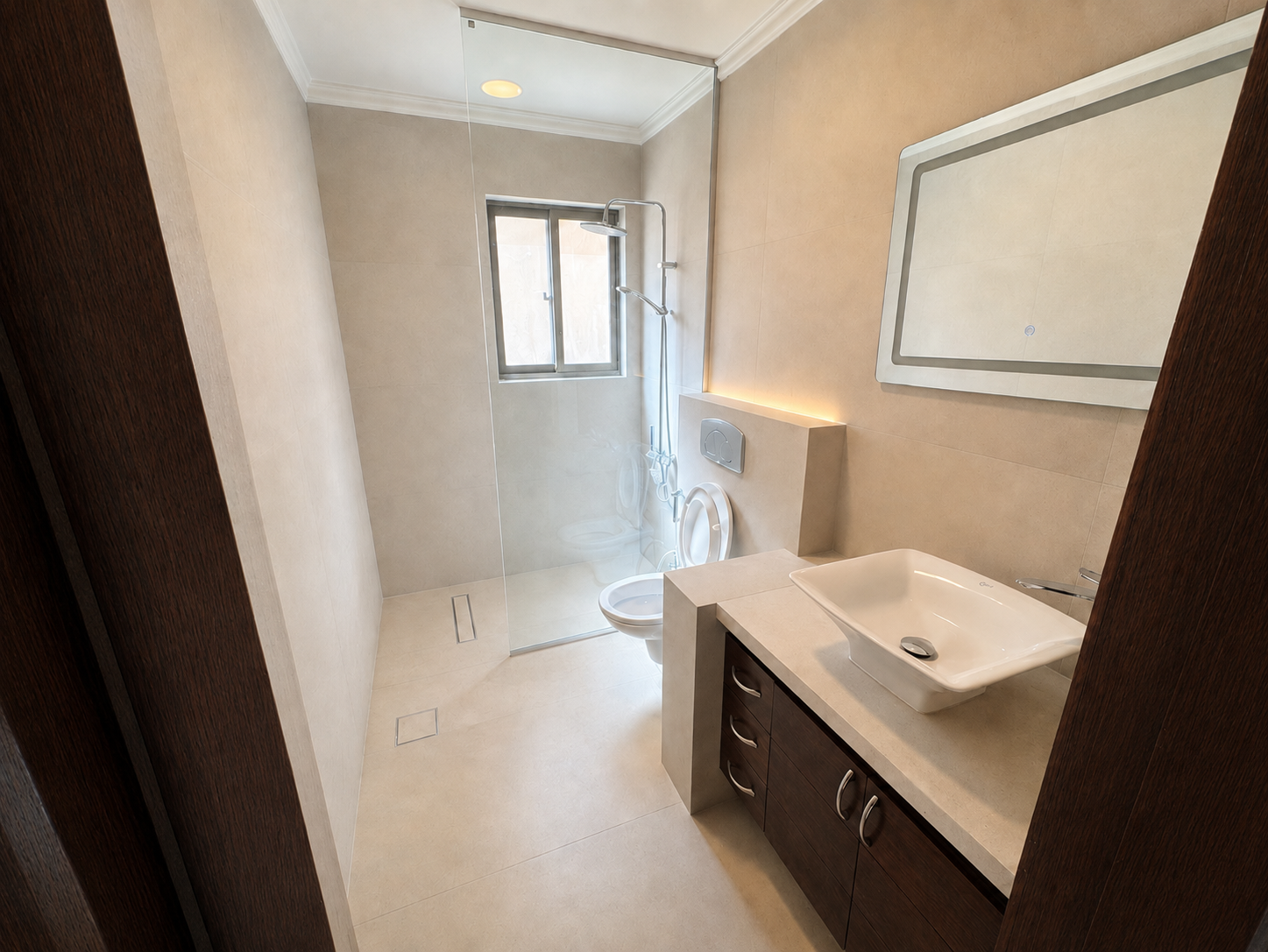 642e47d7-a8bf-438a-a5a9-a41dac83c591 Modern beige-tiled bathroom with glass shower enclosure, wall-mounted toilet, and white rectangular sink.
