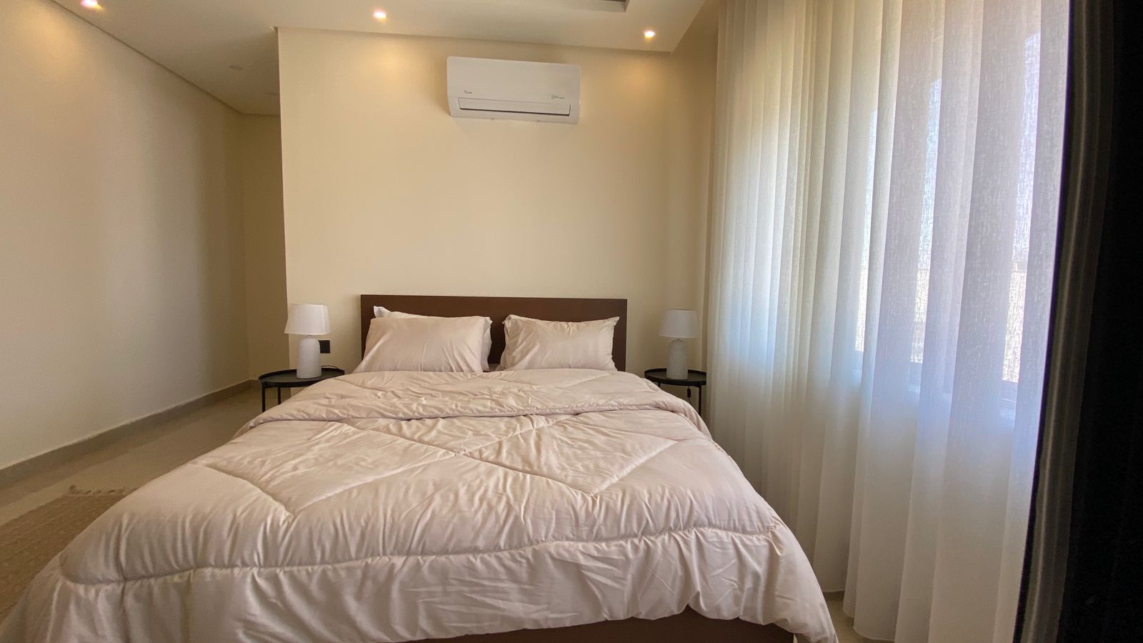 695fb437-452d-4393-ad0a-172f093f47e8 Modern hotel bedroom: a neatly made bed with white duvet, two pillows, and nightstands with lamps.