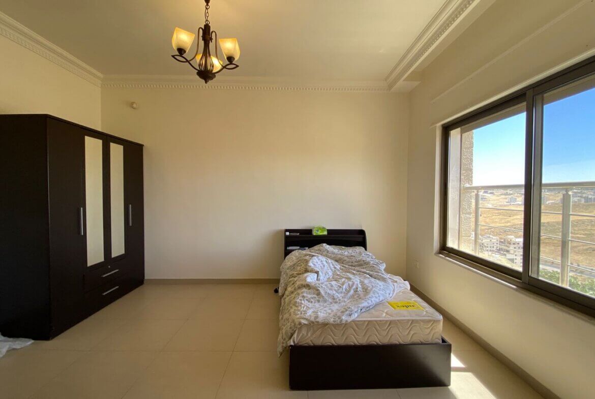 85546a56-23a2-4b67-b8ad-ca91a61d2f06 Bedroom with a single bed near the window, a dark wardrobe on the left, and natural daylight filling the room.