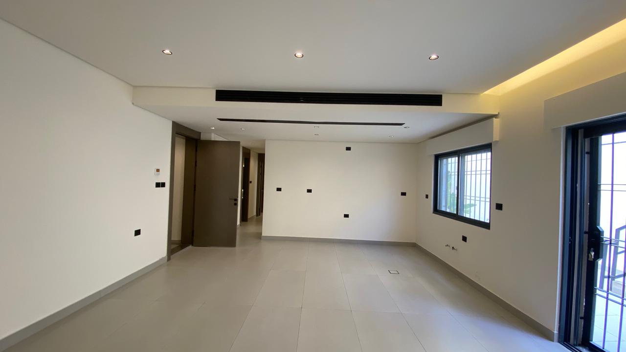 aa1fba2a-295a-40c1-99b2-f47c8802e0cc Empty modern living room with gray floor tiles, white walls, recessed ceiling lights, a large window and balcony door
