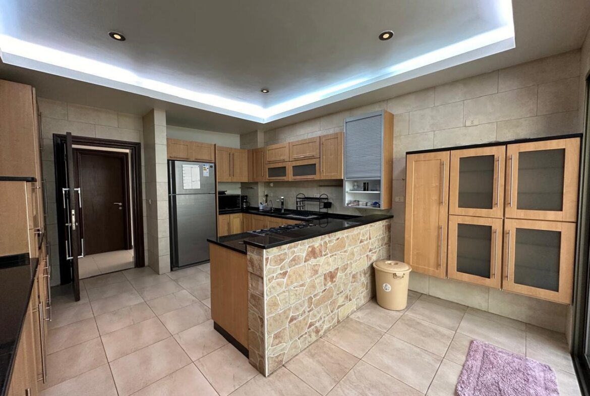Modern kitchen with a stone-front island, wooden cabinets, and stainless steel appliances