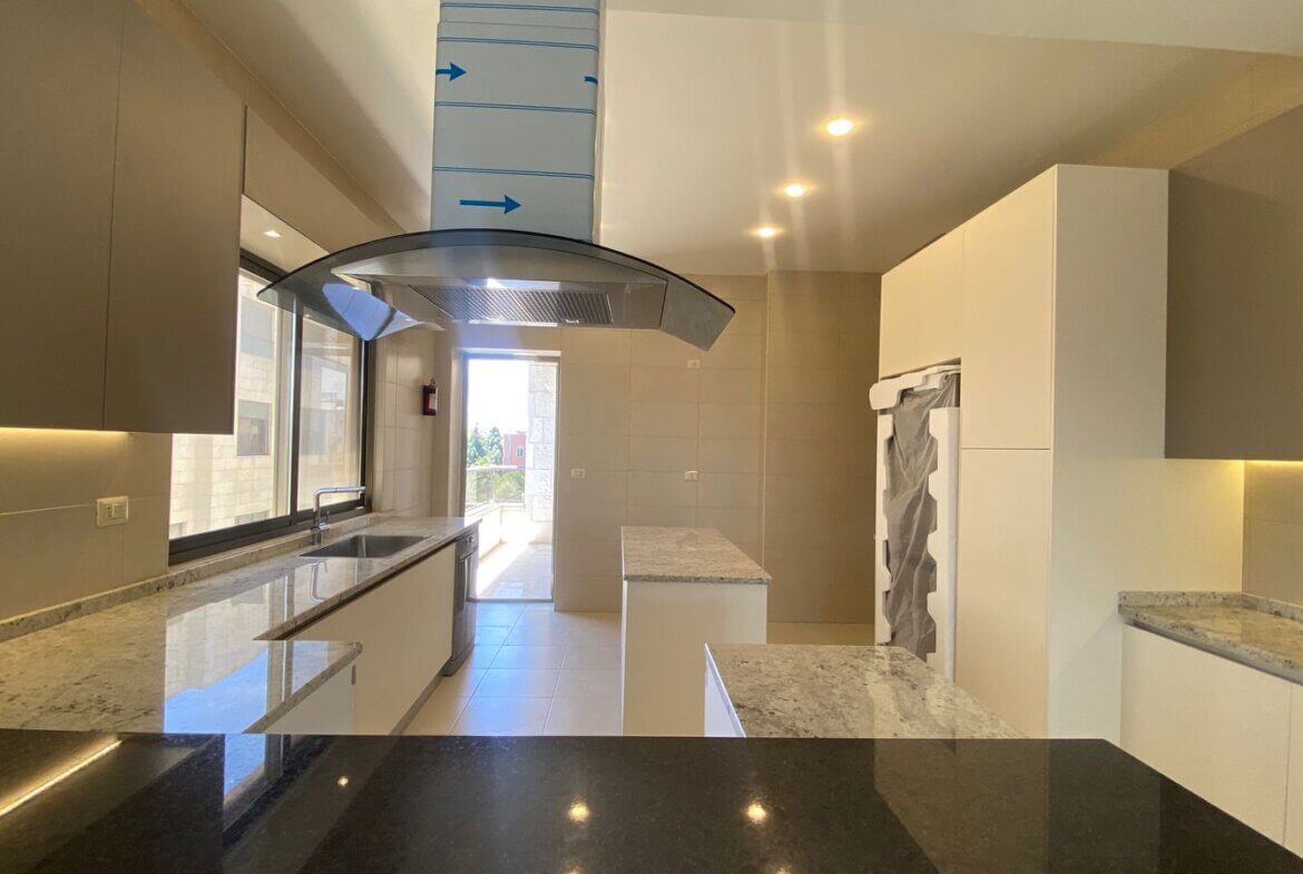 b6c53377-5545-46cb-924c-a0503a698f52 Bright modern kitchen with white cabinets, granite countertops, an island, and a curved glass range hood under a tall vent duct marked with blue arrows.