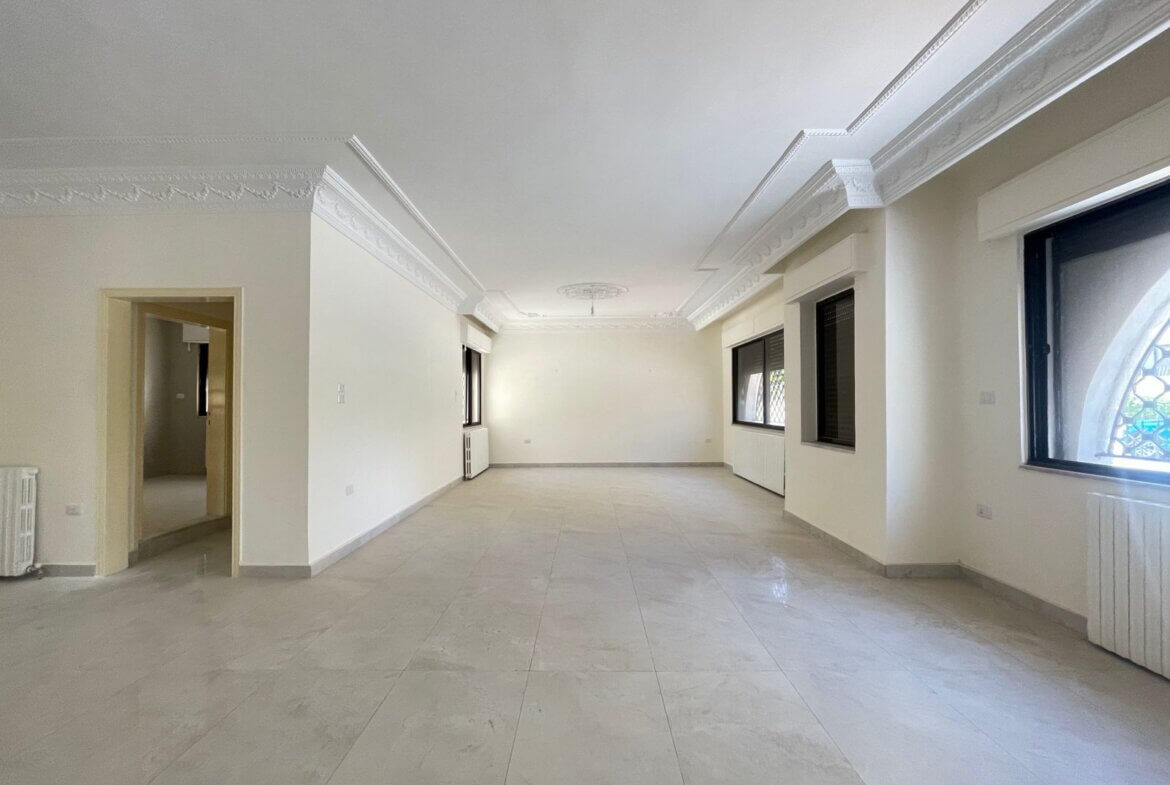 c0a710e1-4eb8-4674-91f6-0259a5b2e02c Bright, unfurnished living room with ornate plaster molding along the ceiling and large side windows.