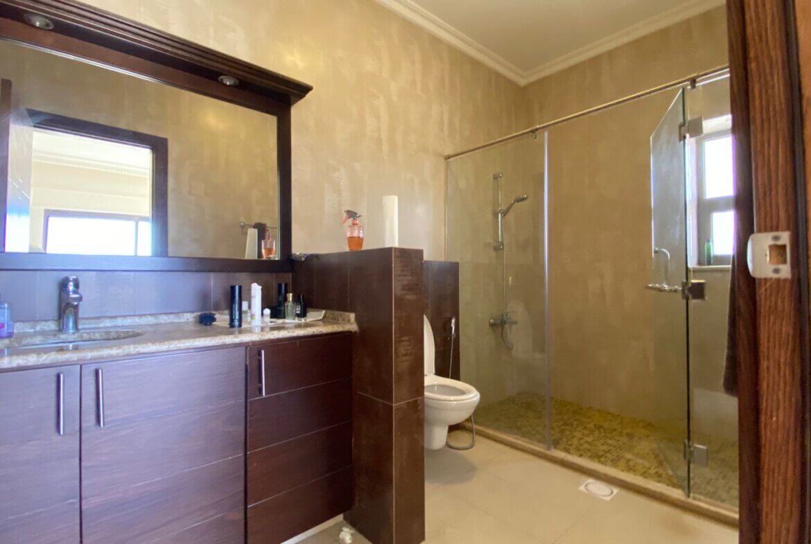 c8e5a28c-4fad-4e49-8cd1-e7c8a6060ca9 Modern bathroom with a dark wood vanity, marble countertop, large mirror, and a glass-enclosed shower.
