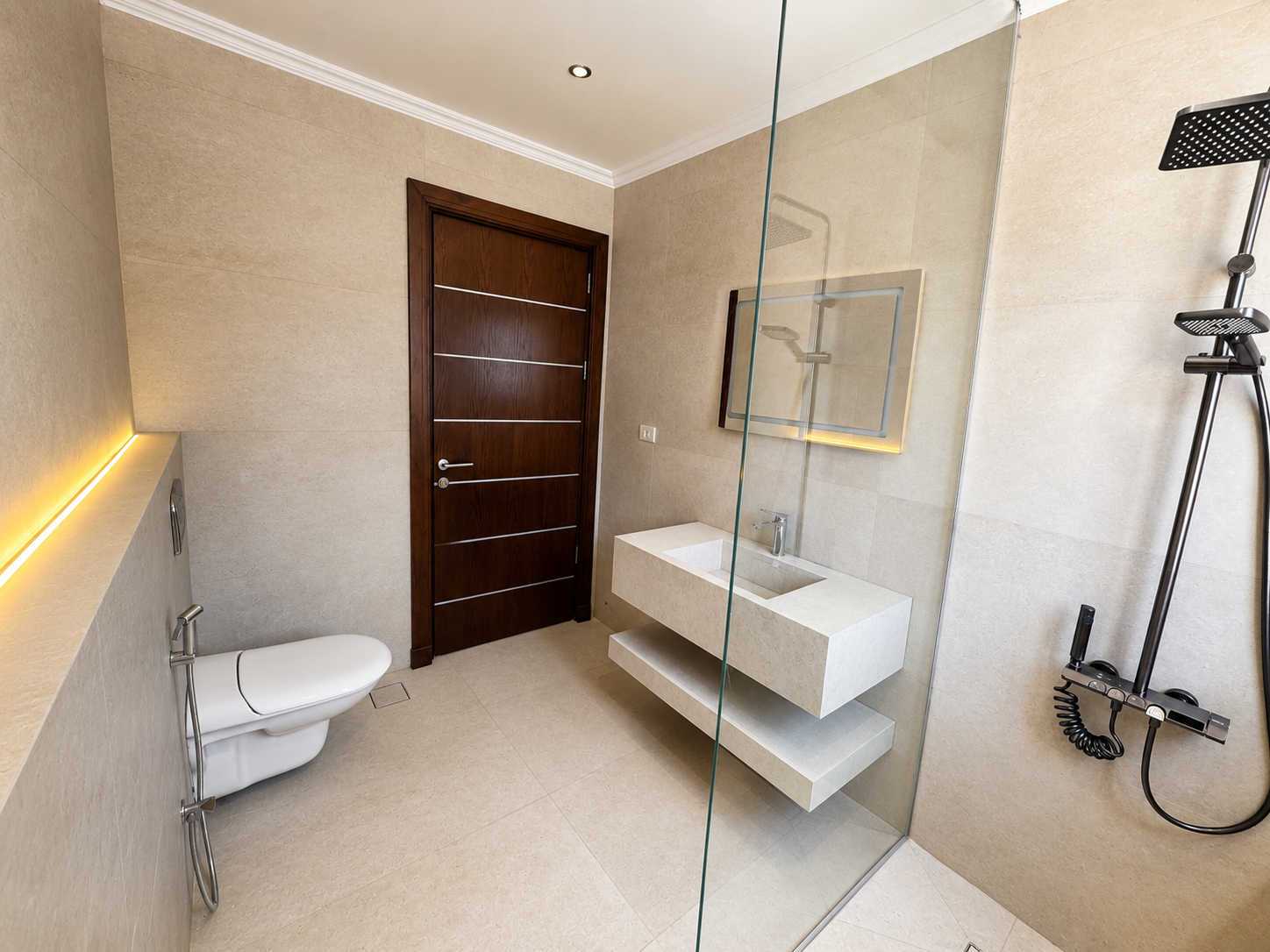d3057bbb-dc7a-437c-bdd5-4aa3d0518dac Modern beige-tiled bathroom with a dark wooden door, wall-mounted concrete sink, and glass-enclosed shower area.
