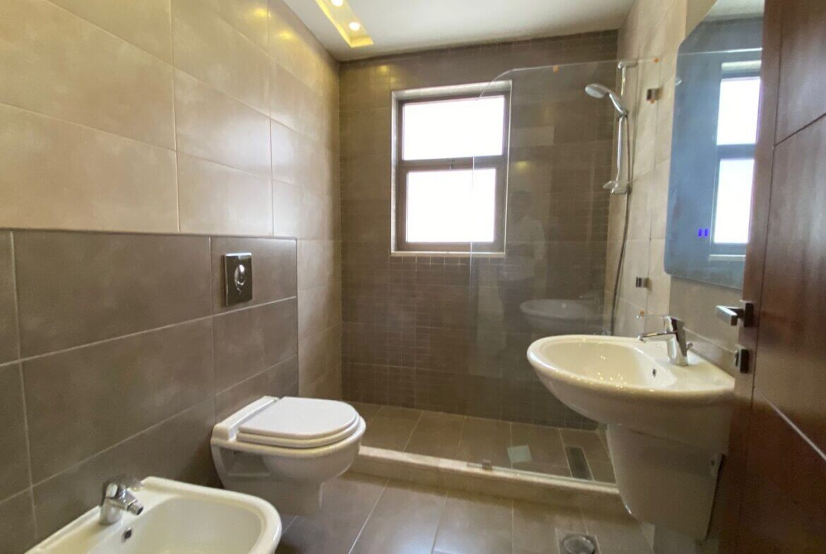 e810125c-eb84-4a61-a507-27f82fcb1ce9 Modern bathroom with a glass-enclosed shower, wall-mounted toilet, and pedestal sink