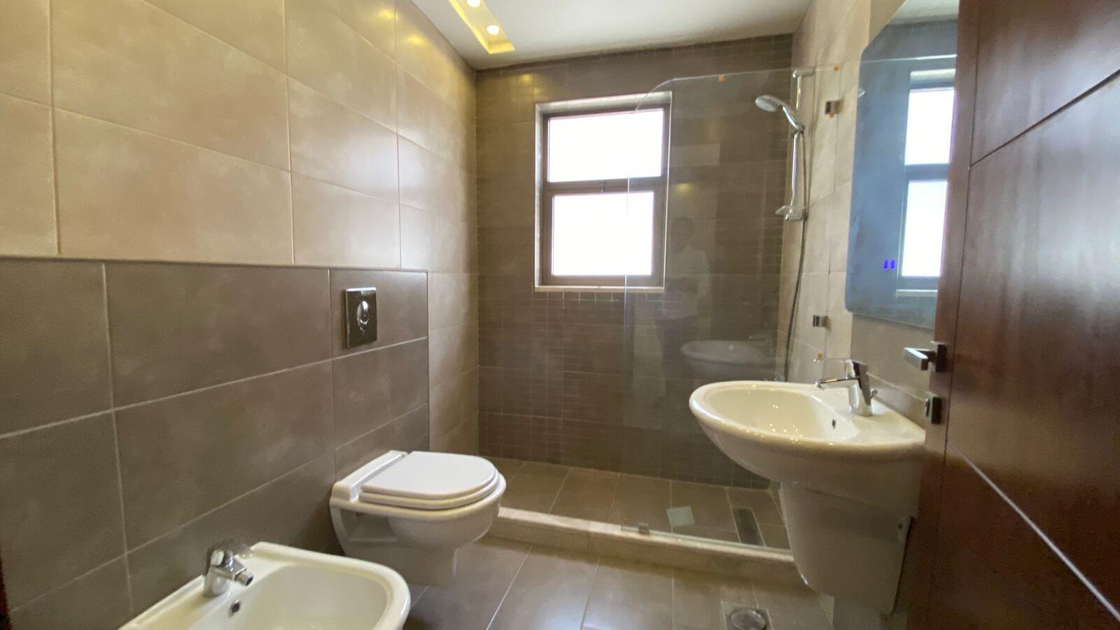 e810125c-eb84-4a61-a507-27f82fcb1ce9 Modern bathroom with a glass-enclosed shower, wall-mounted toilet, and pedestal sink