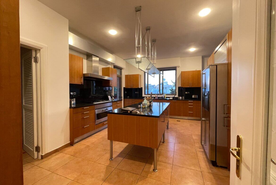 fe3d5f56-1905-4548-931d-d4cc54606296 Modern kitchen with a central island, wooden cabinets, stainless steel appliances, and a large window.