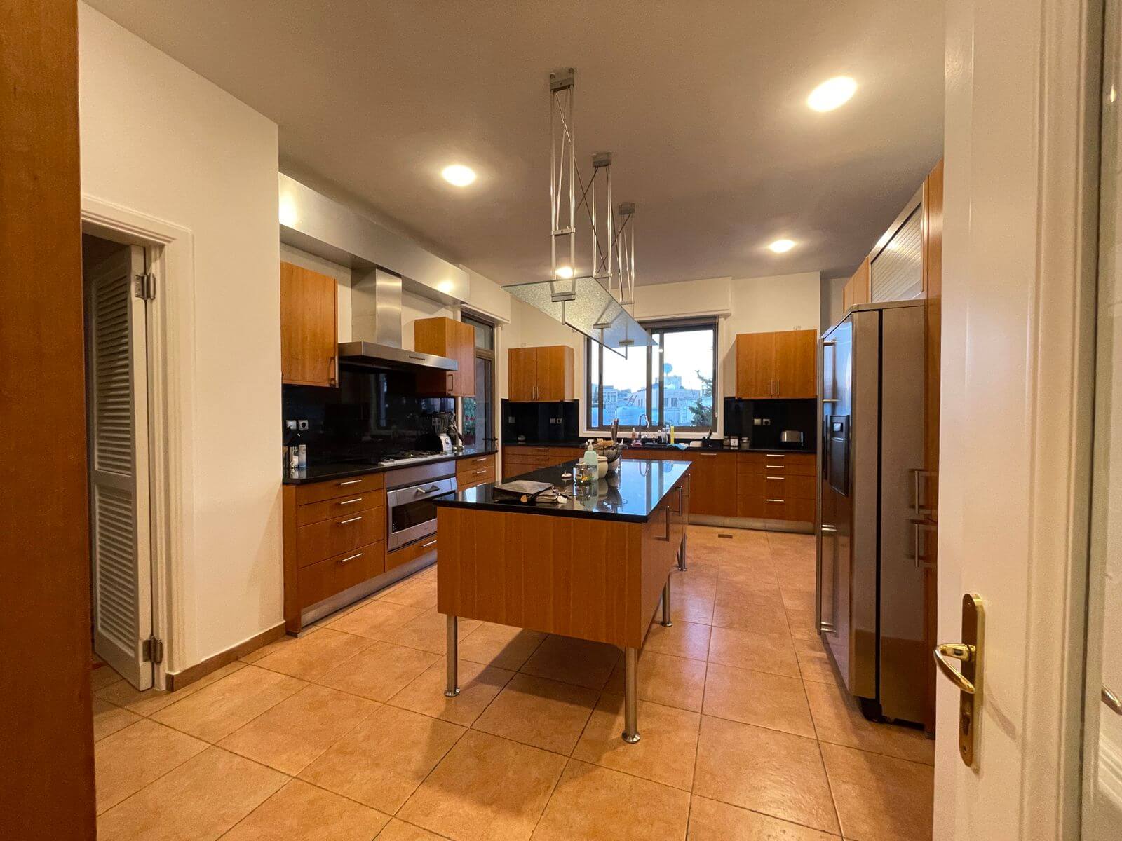 fe3d5f56-1905-4548-931d-d4cc54606296 Modern kitchen with a central island, wooden cabinets, stainless steel appliances, and a large window.